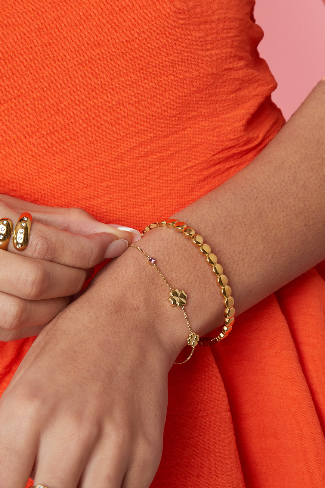 Detail van klaverarmband met roze stenen en strass